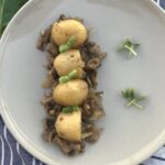 Plated breakfast potatoes with sautéed mushrooms garnished with microgreens.