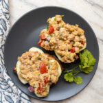 Chickpea salad sandwich spread served on slices of bread with fresh cilantro, placed on a black plate.