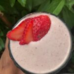 Close-up view of a creamy peanut butter strawberry smoothie topped with fresh strawberry slices.